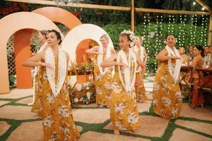 Dancers in gold floral dresses perform on a decorated stage with large circular backdrops.