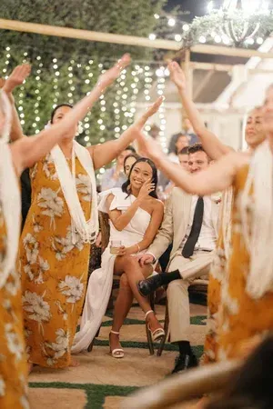 People dancing at an outdoor evening celebration with string lights and a seated guitarist