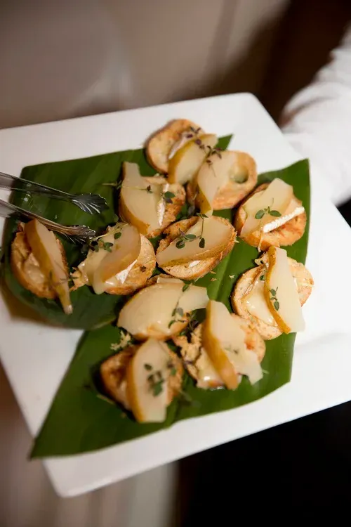 Plated stuffed dumplings on green banana leaves on a white square plate