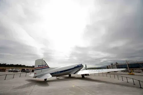 Jet parked on the tarmac under a cloudy sky, with a steep nose-up angle and extended stairs.