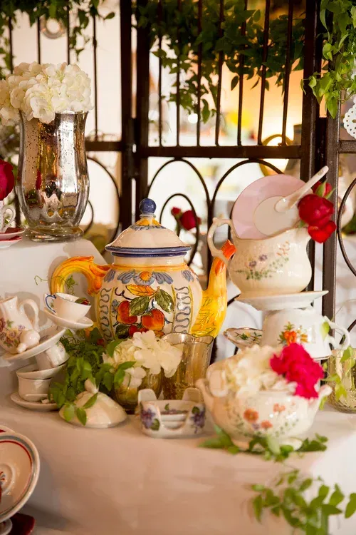 Elegant tea table with floral china, teapot, cups, and white flowers in a bright garden setting