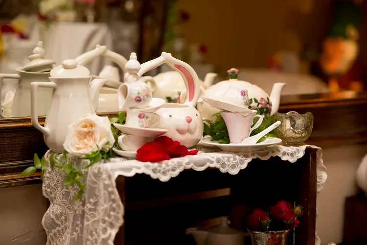 Tea set and floral teacups on a lace-covered table with a red rose centerpiece