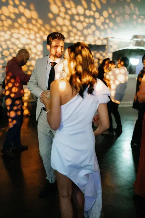 People dancing at a party with warm disco light patterns on the walls