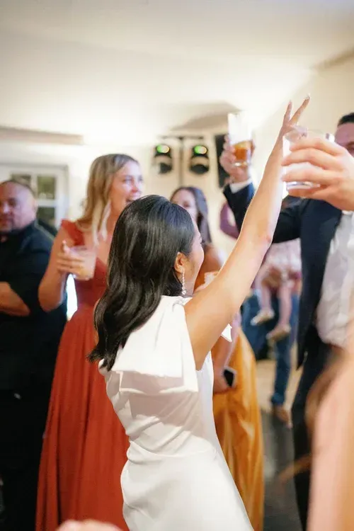 Guests dancing and raising glasses at an indoor celebration