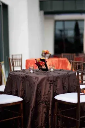 Outdoor café table with brown tablecloth and chairs in front of a building