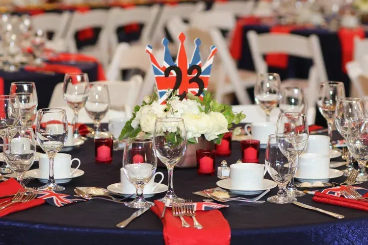 Formal banquet table with red, black, and white decorations and a floral centerpiece numbered 23