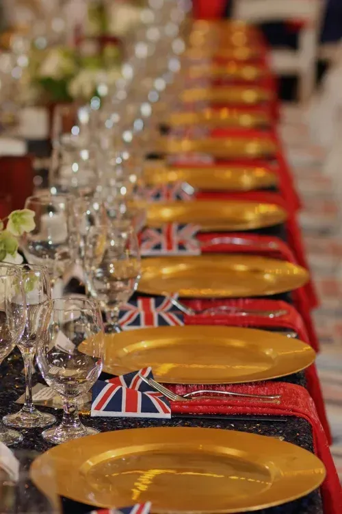 Long banquet table set with gold plates, wine glasses, and Union Jack napkins