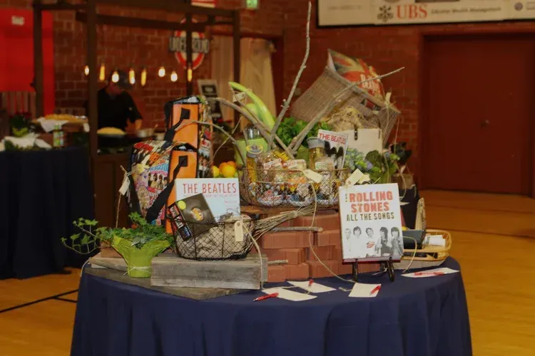 Gift baskets and prize signs displayed on a blue-draped table in a banquet hall