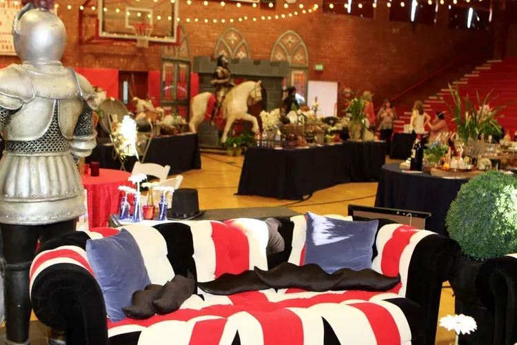 Decorated event lounge with a red, black, and white couch, silver armor display, and festive tables and lights