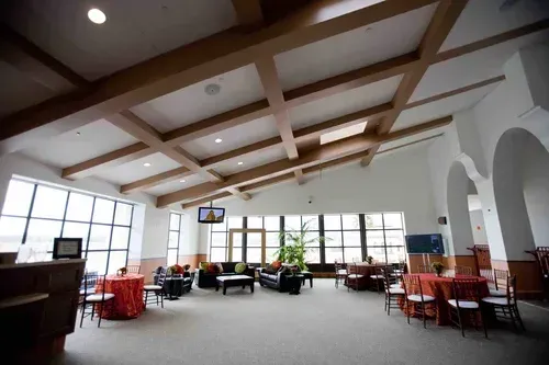 Bright café interior with wooden beams, large windows, and red tables and chairs