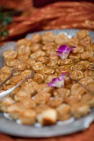 Tray of golden fried snacks topped with purple flowers on a buffet table