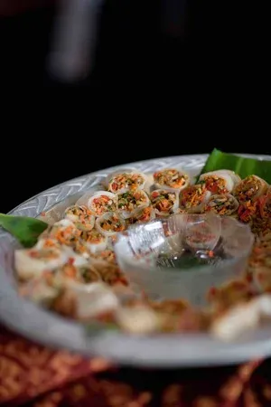 Tray of colorful sushi rolls arranged in a circle with a dipping sauce in the center.