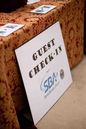 Guest check-in sign beside a table with patterned cloth and small cards, labeled “SBP” under the sign.