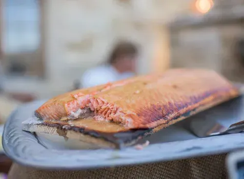 Grilled salmon fillet on a plate, with a blurred indoor dining background