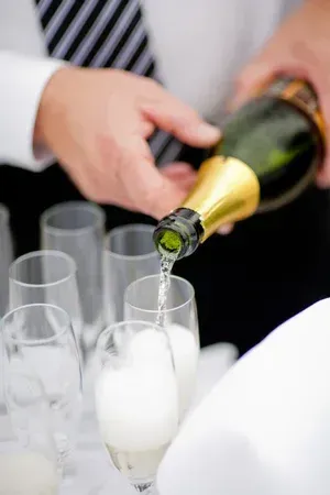 A person pours champagne into flutes at a celebration.