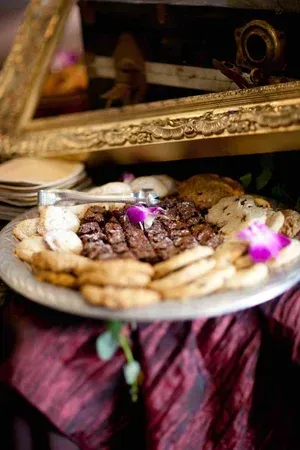 Tray of assorted sweets and pastries with purple flowers, under a decorative gold mirror frame