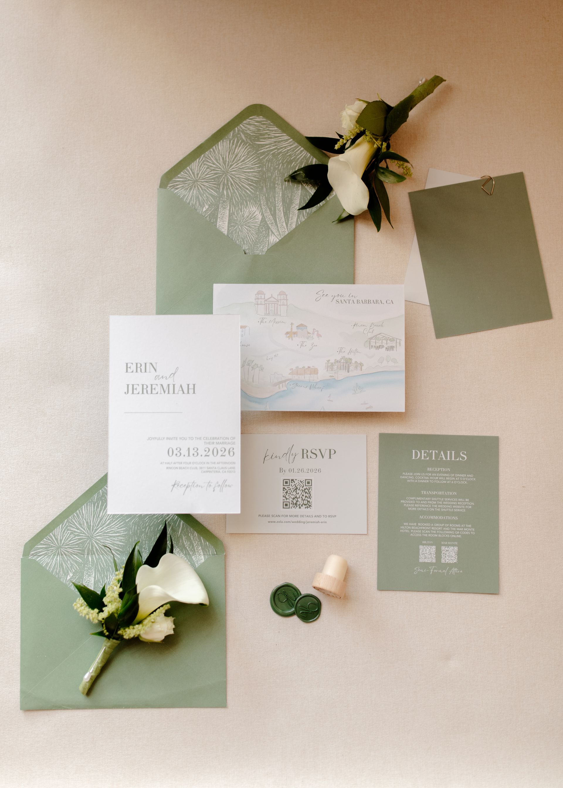 Wedding invitation suite with green and white cards, greenery, and cream flowers arranged on a beige background