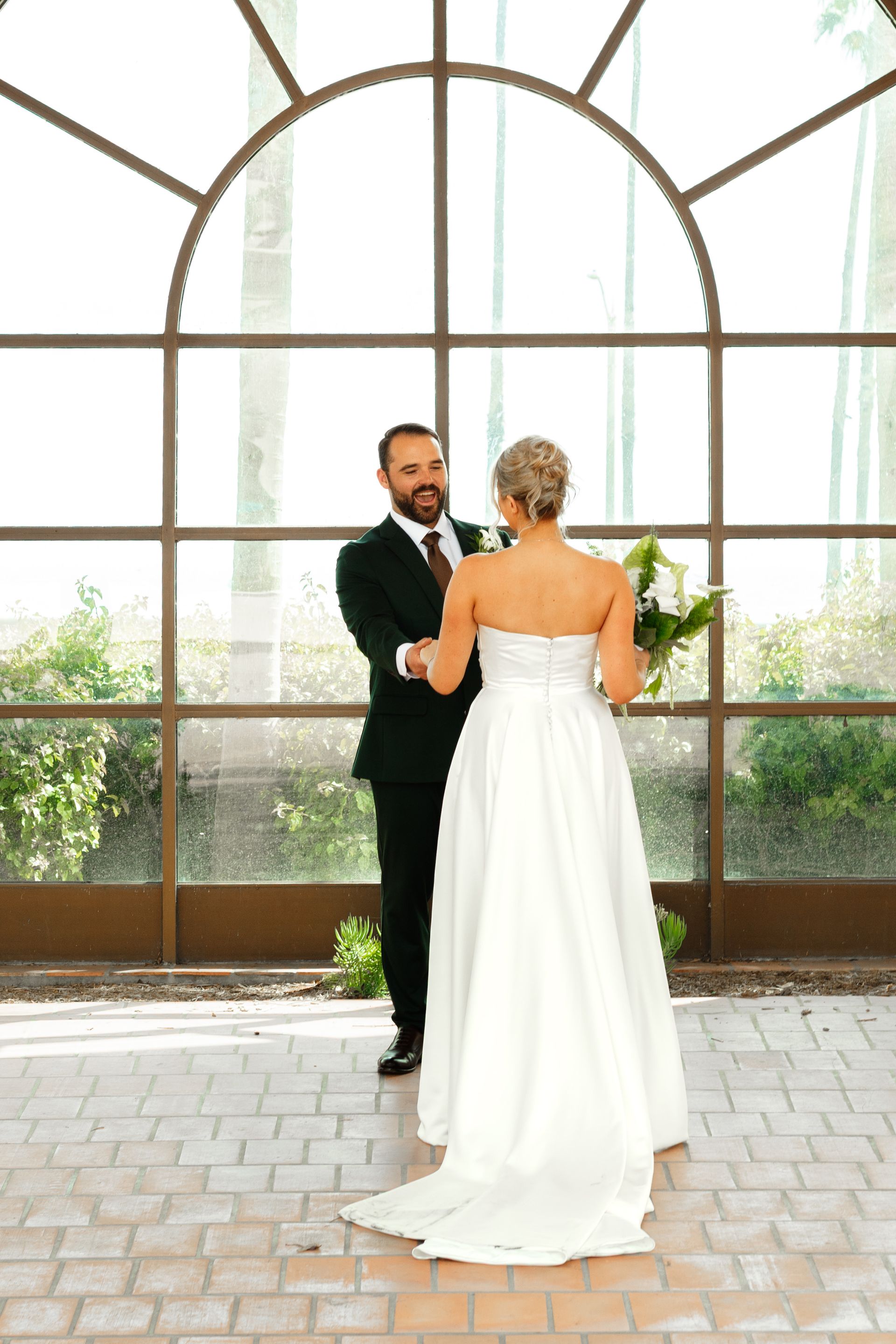 Bride and groom dancing in a bright arched-window venue