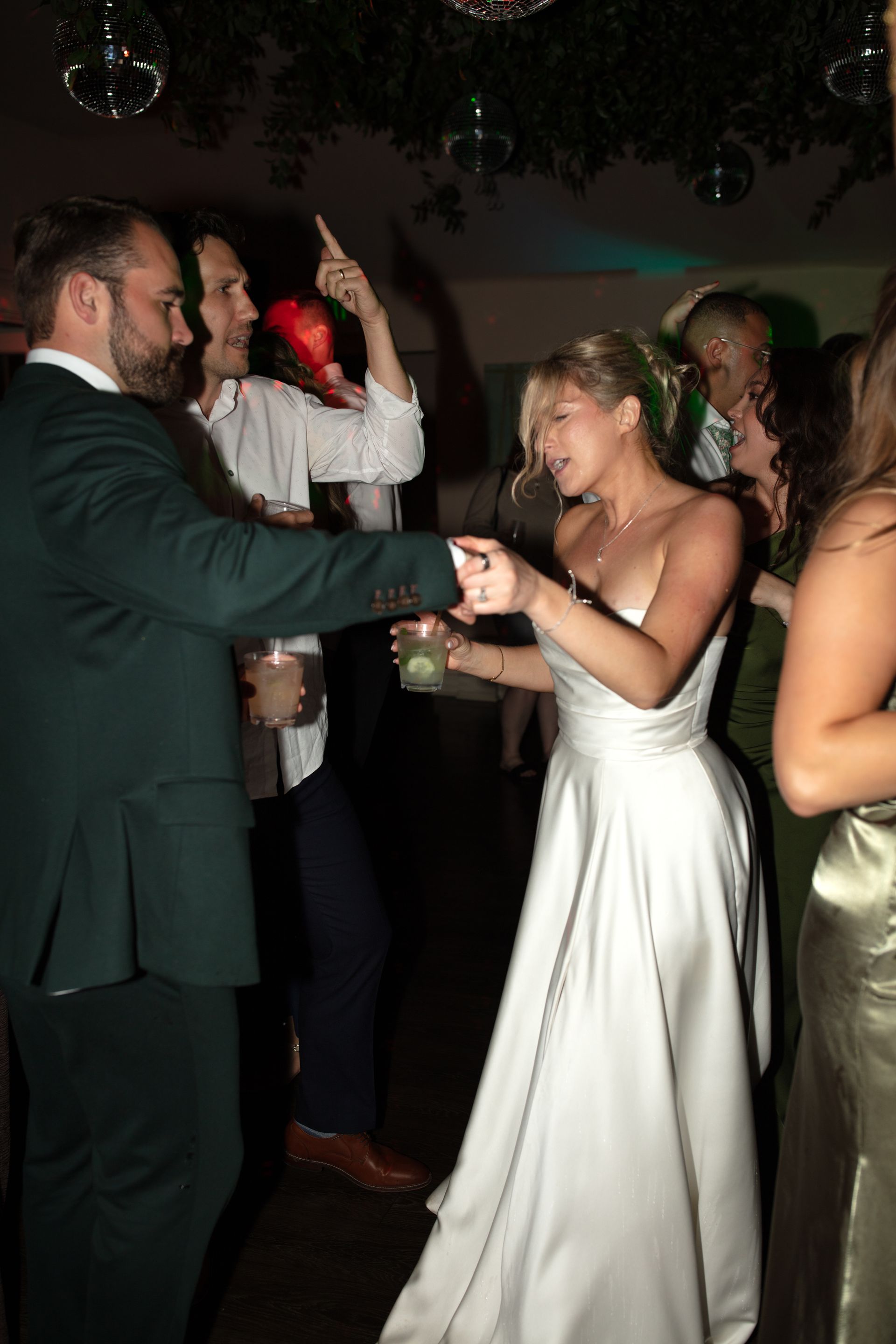 Couple dancing at a dimly lit party, with the woman in a white dress and the man in a dark suit.