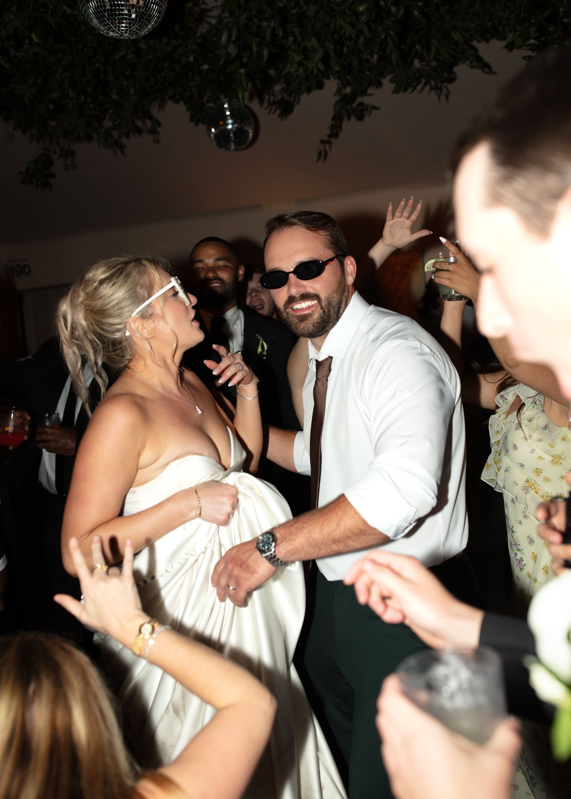 Smiling couple dancing at a crowded party, with raised hands around them