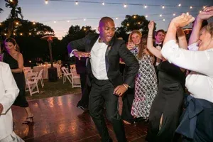 People dancing at an outdoor evening celebration under string lights