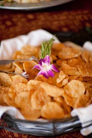 Basket of crispy chips topped with a purple orchid flower, served on a table