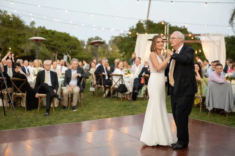 Bride and groom dancing at an outdoor wedding reception under string lights