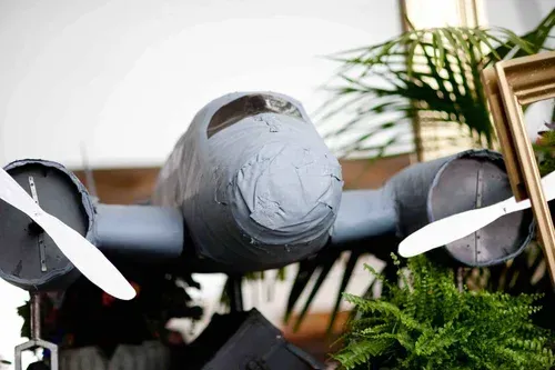 A gray model airplane with white wings displayed among green plants indoors