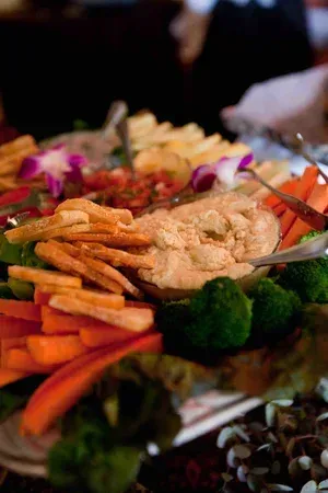 Buffet platter with fried snacks, carrot sticks, broccoli, and dips on a serving tray