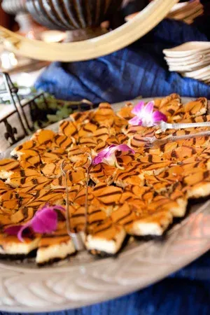 Plated dessert with caramel drizzles and pink edible flowers on a table