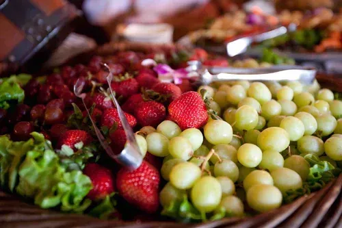 Basket of fresh strawberries, green grapes, and lettuce at a market stall