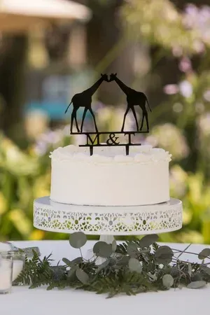 Wedding cake with giraffe topper and floral greenery on a decorated table