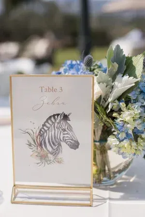 Table 3 sign with zebra illustration beside a blue-and-white floral arrangement on a white table