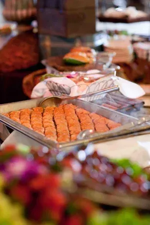 Buffet table with trays of grilled salmon and other dishes at a catered event