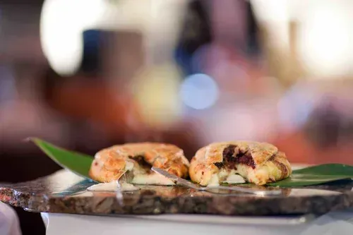 Two stuffed pastry pieces on a tray with green garnish, blurred restaurant background