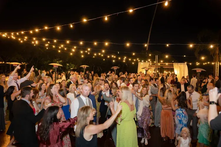 Crowd dancing under string lights at an outdoor evening celebration