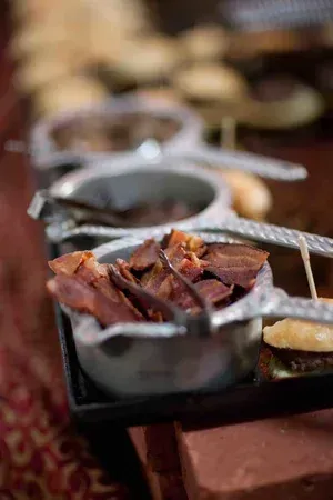Small metal bowls of roasted food on a serving tray, with warm brown tones.