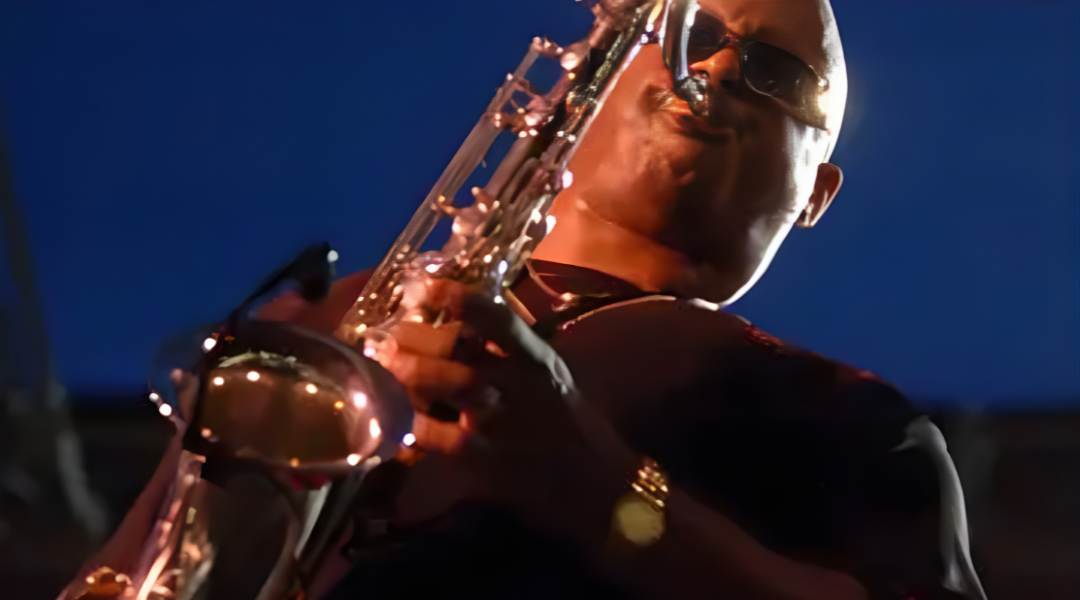 Close-up of a saxophonist playing under blue stage lighting at night