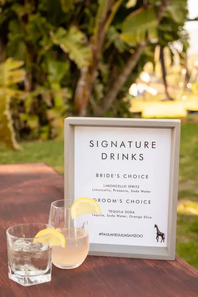 Signature drinks sign beside two lemon cocktails on a wooden table outdoors