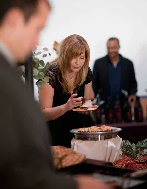 Woman serving herself food at a buffet table during a social gathering