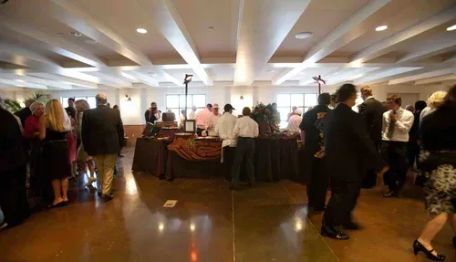 People gathered around a buffet table in a bright banquet hall.
