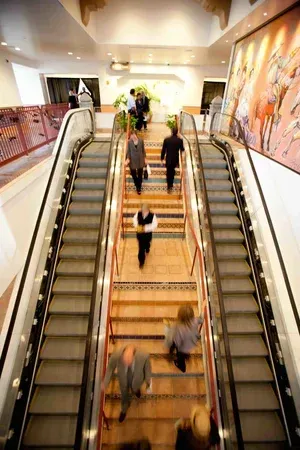 People riding twin escalators in a bright indoor mall hallway