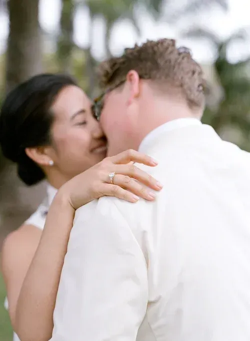 Close-up of two people kissing outdoors, with a blurred green background.