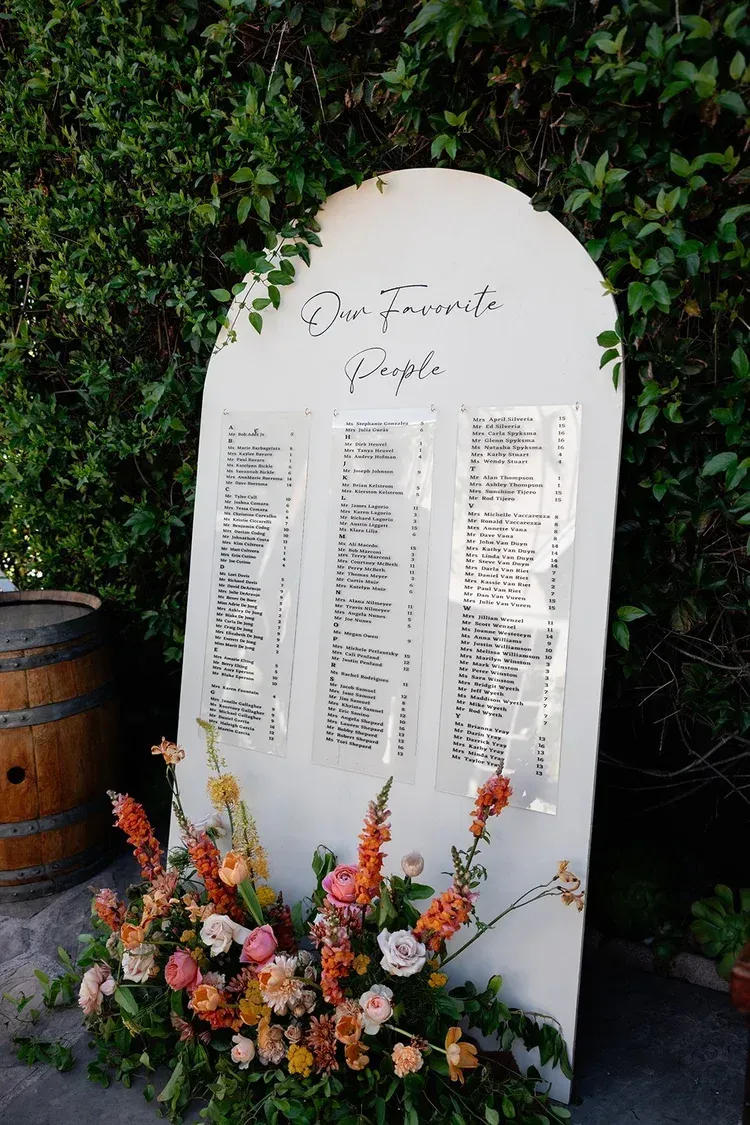 White memorial plaque with floral arrangement in front of ivy-covered wall