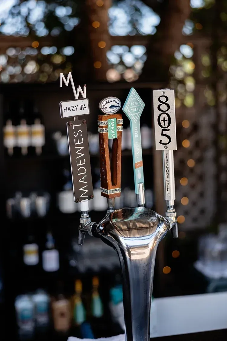 Beer taps on a bar counter with blurred bottles in the background.