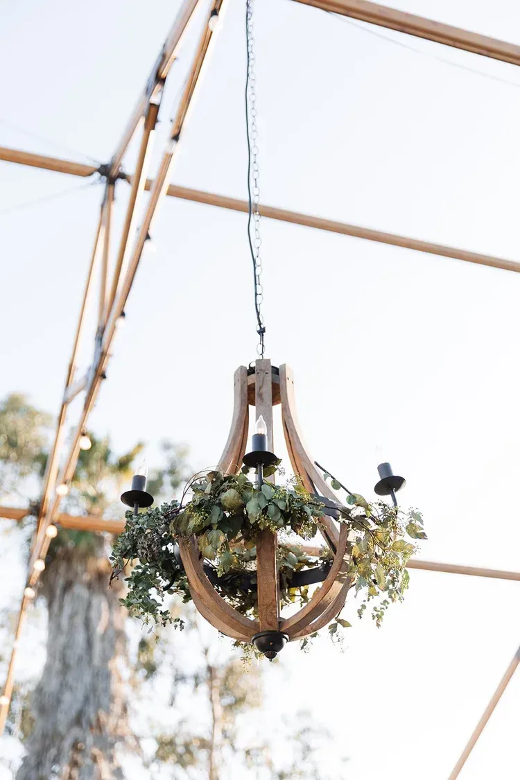 Wooden hanging floral chandelier with greenery under a tented event canopy