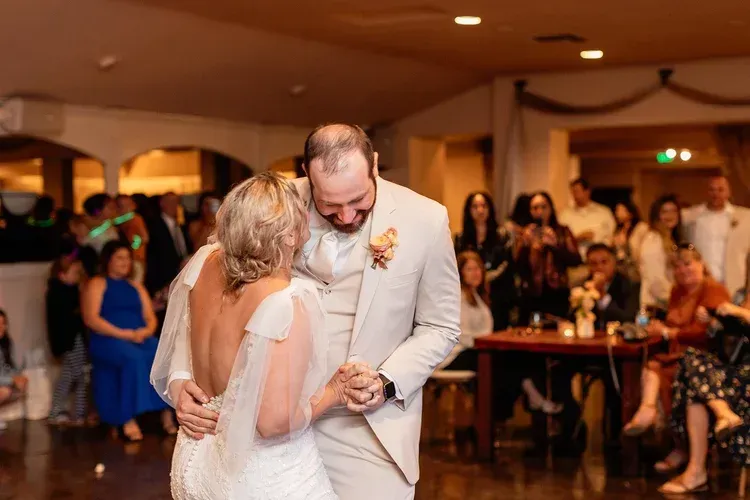 Couple slow dancing at a wedding reception in a warmly lit hall