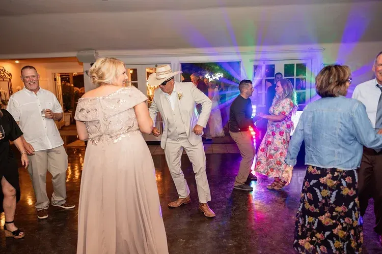 Guests dancing at a wedding reception with colorful party lights and formal attire