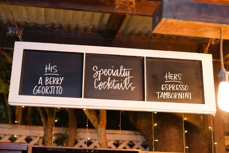 Three chalkboard signs in a rustic bar listing beer, specialty cocktails, and espresso martini options