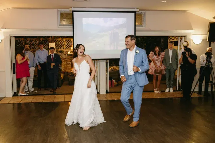 Bride and groom dancing at a wedding reception, guests watching in the background